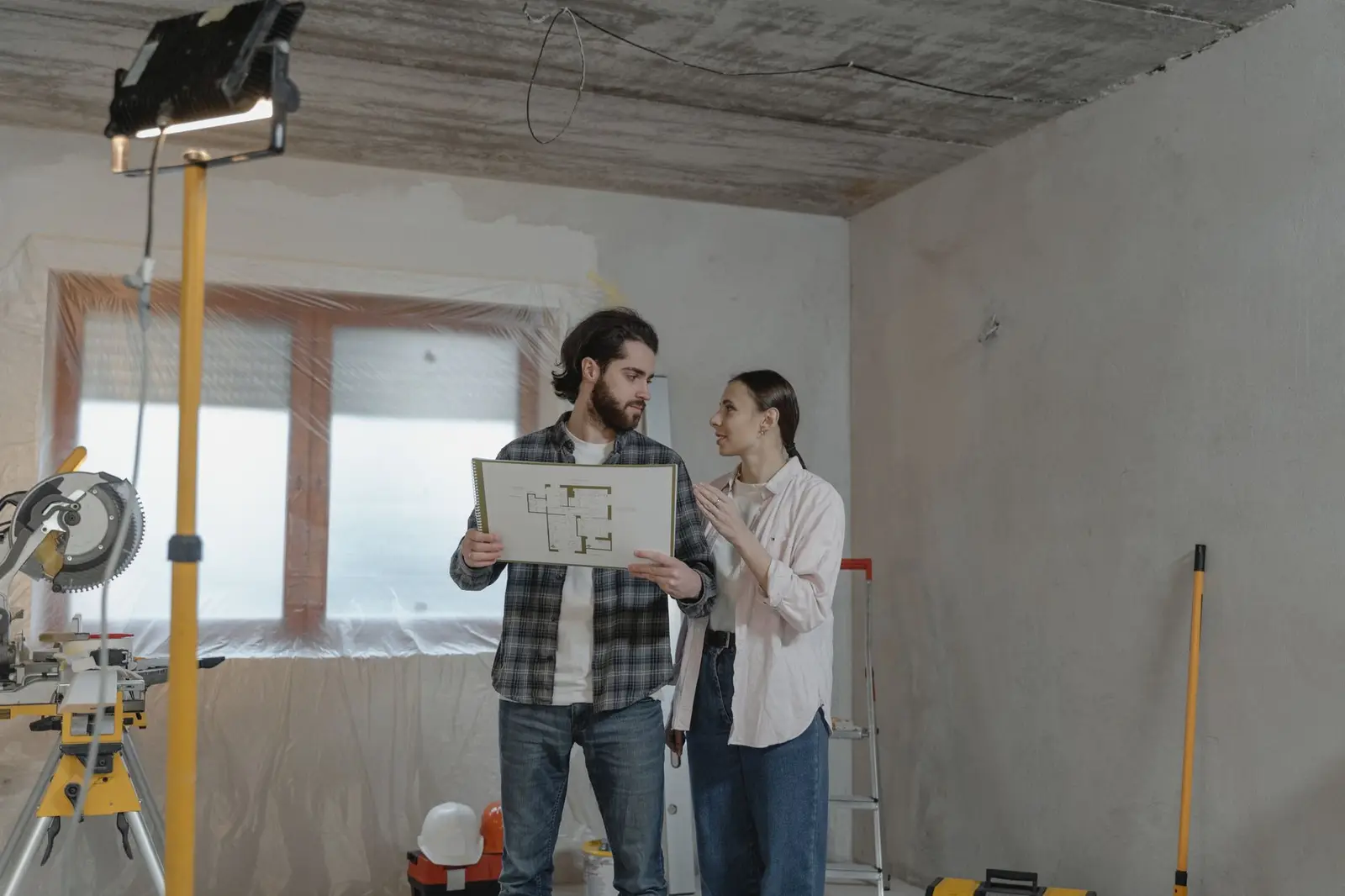 Deux personnes relisent un plan sur un chantier